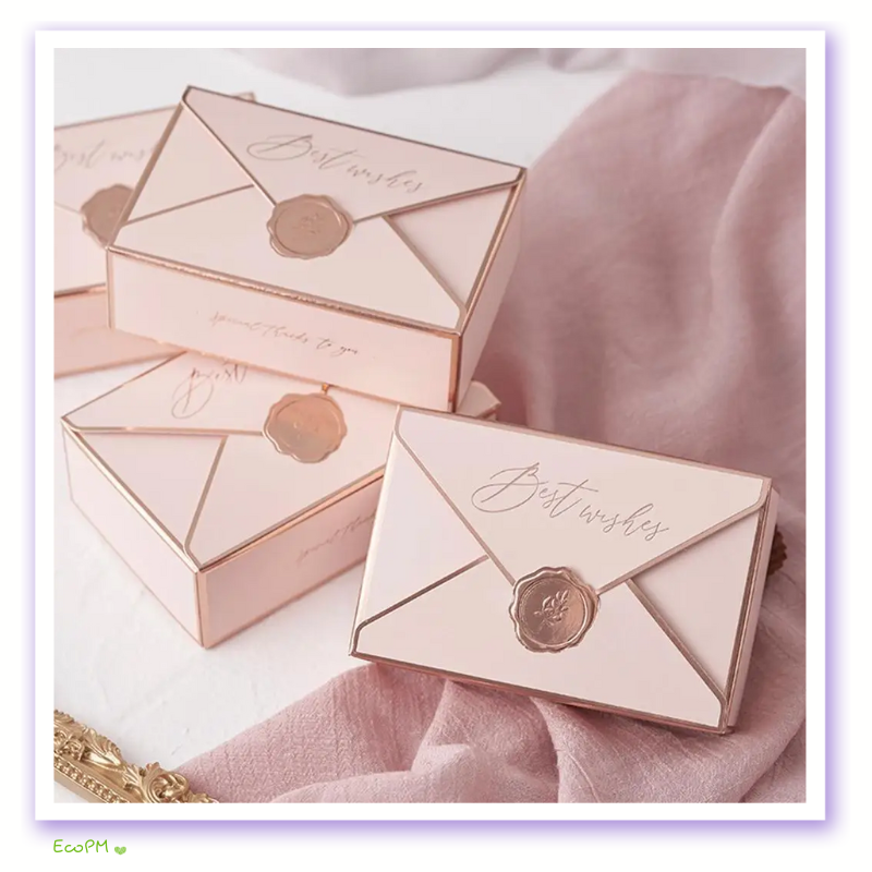 blush-envelope-favor-box-gold-seal.png A blush pink favor box designed to mimic an envelope, complete with a sophisticated gold wax seal, radiating elegance and warmth.