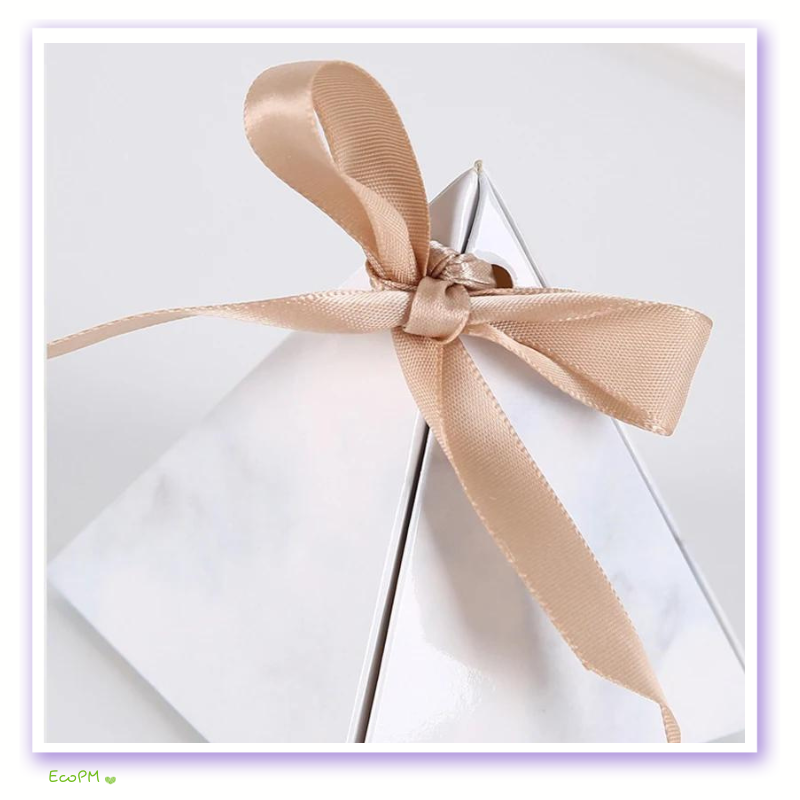 marble-pyramid-favor-box-satin-ribbon.jpg Close-up of a marble-patterned pyramid favor box tied with a satin champagne ribbon, ideal for elegant event giveaways.