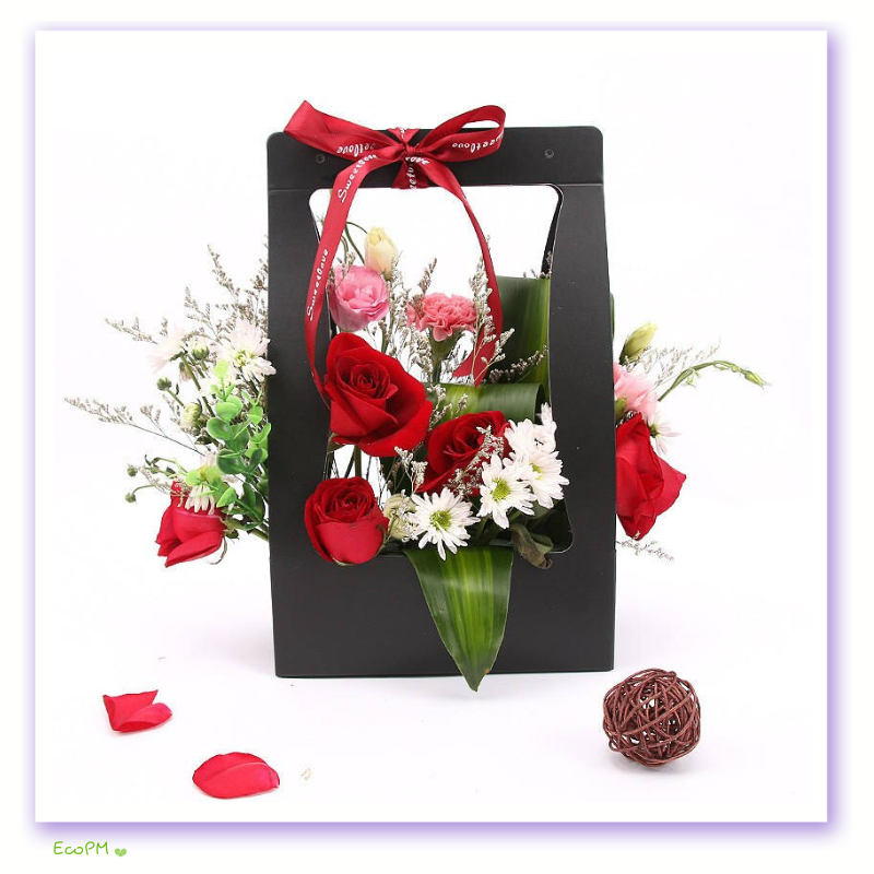 black-eco-floral-gift-bag.png Black eco-friendly floral gift bag with a red ribbon and a vibrant selection of flowers.