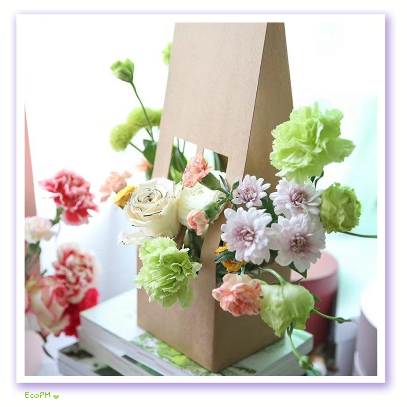 eco-friendly-kraft-paper-flower-bag.png Eco-friendly kraft paper bag with a handle, showcasing a delightful assortment of fresh flowers including white roses and green carnations.