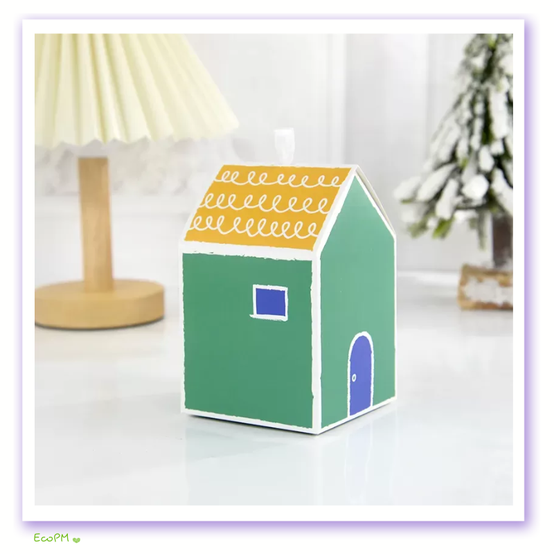emerald-cottage-favor-box.png Green miniature house favor box with yellow scalloped roof and blue door detail.