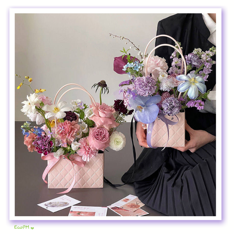pastel-floral-paper-bag.jpg Elegant pastel paper bag with assorted fresh flowers arrangement, held by a person in a black outfit.