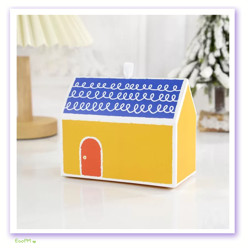 sunny-cottage-favor-box.png Bright yellow miniature house favor box with blue scalloped roof detailing.