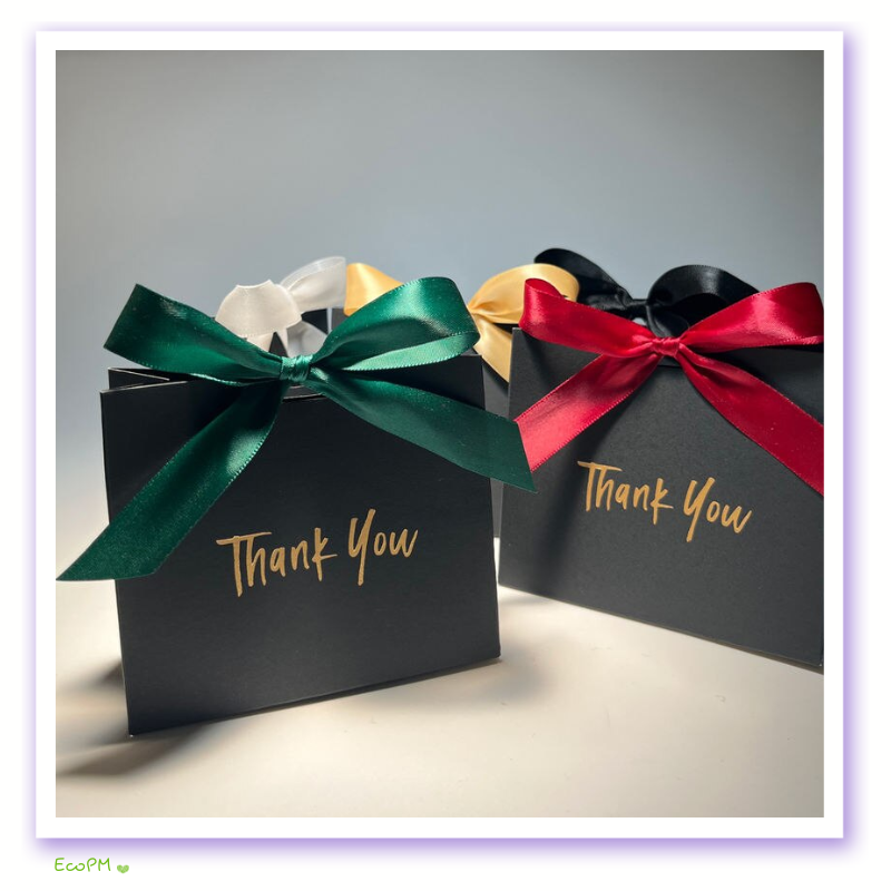 Appreciation-Themed Gift Boxes with Satin Ribbon Accents Black gift boxes with 'Thank You' in gold script, adorned with luxurious satin ribbons in emerald green, gold, and crimson.