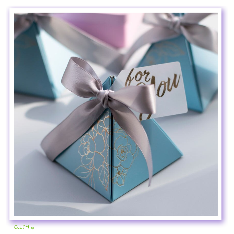 elegant-pyramid-favor-boxes-with-satin-ribbons.png Elegant blue pyramid favor boxes with gold floral print and gray satin ribbons, perfect for wedding and party gifts.