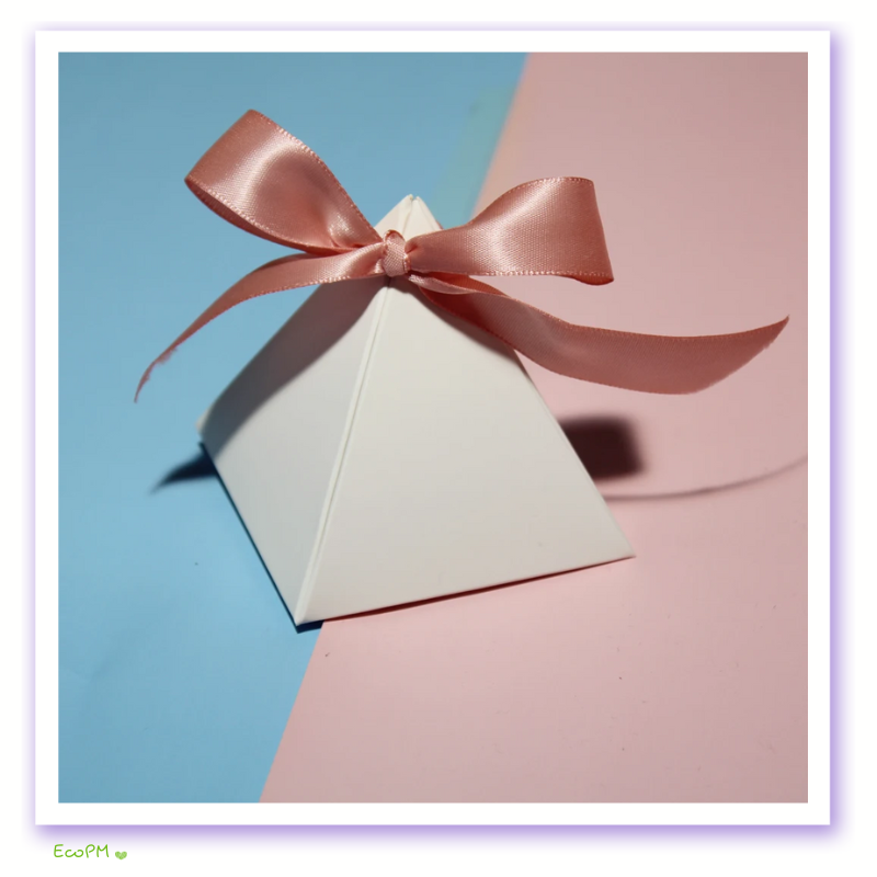 elegant-white-pyramid-gift-box-pink-ribbon.png Elegant white pyramid gift box with a soft pink satin ribbon on a pastel pink and blue background.